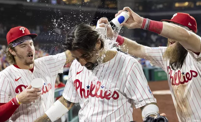 Philadelphia Phillies' Nick Castellanos, center, is doused with water by Bryson Stott, left, and Brandon Marsh after their team shut out the Houston Astros in a baseball game, Tuesday, Aug. 27, 2024, in Philadelphia. (AP Photo/Laurence Kesterson)