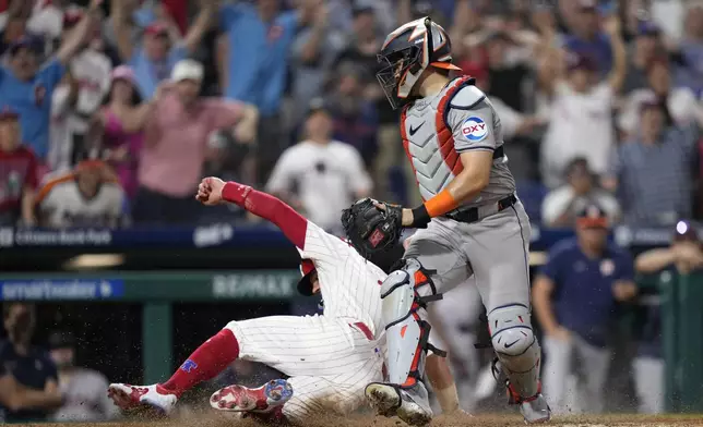 Philadelphia Phillies' Kyle Schwarber, left, scores the game-winning run past Houston Astros catcher Yainer Diaz on an RBI-single by Bryce Harper during the 10th inning of a baseball game, Monday, Aug. 26, 2024, in Philadelphia. (AP Photo/Matt Slocum)