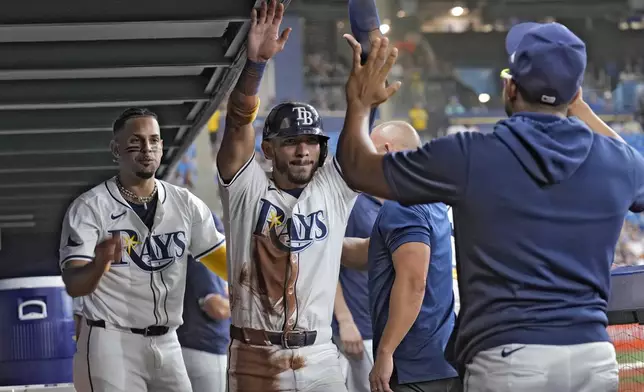 Tampa Bay Rays' Jose Caballero, center, celebrates with Christopher Morel, right, and Richie Palacios, left, after scoring on an RBI single by Josh Lowe off Houston Astros starting pitcher Yusei Kikuchi during the second inning of a baseball game Tuesday, Aug. 13, 2024, in St. Petersburg, Fla. (AP Photo/Chris O'Meara)