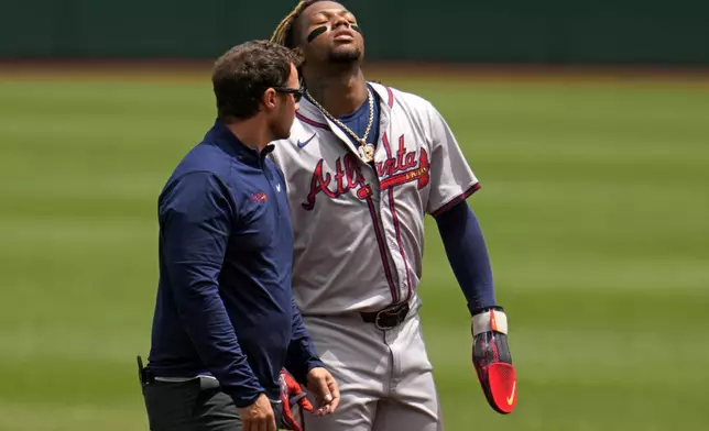 FILE - Atlanta Braves' Ronald Acuña Jr., right, walks off the field with a trainer after being injured while running the bases during the first inning of a baseball game against the Pittsburgh Pirates in Pittsburgh, Sunday, May 26, 2024. (AP Photo/Gene J. Puskar, File)