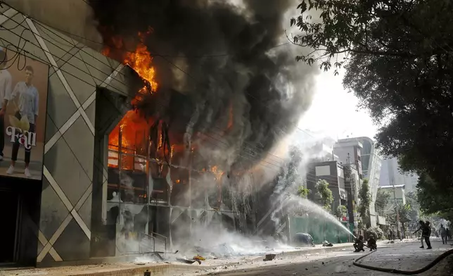 Firefighters douse a fire engulfing a shopping center which was set on fire by protesters during a rally against Prime Minister Sheikh Hasina and her government demanding justice for the victims killed in the recent countrywide deadly clashes, in Dhaka, Bangladesh, Sunday, Aug. 4, 2024. (AP Photo/Rajib Dhar)