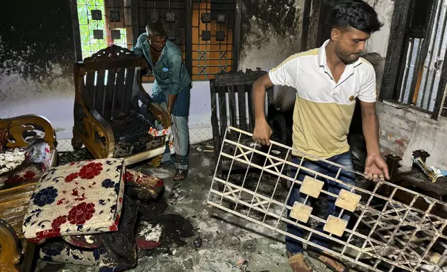 Relatives salvage furniture from a house belonging to a supporter of Bangladesh's former prime minister that was burnt down by a mob, in Dhaka, Bangladesh, Sunday, Aug. 11, 2024. (AP Photo/Al-emrun Garjon)