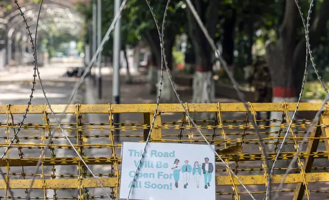 A sign saying 'This road will be open for all soon!' is posted on a barricade as protesters block the road in front of the former residence of Sheikh Mujibur Rahman, father of the ousted Prime Minister Sheikh Hasina, on his death anniversary in Dhaka, Bangladesh, Thursday, Aug. 15, 2024. (AP Photo/Rajib Dhar)