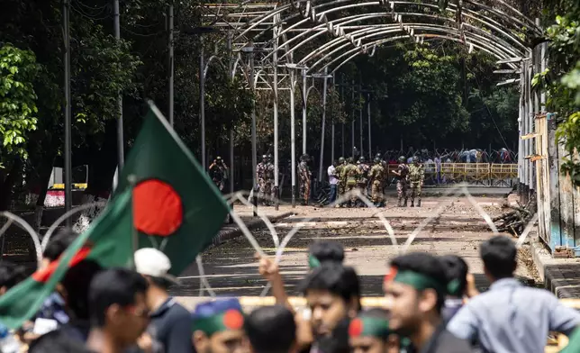 Military and paramilitary personnel stand guard as protesters block the road in front of the former residence of Sheikh Mujibur Rahman, father of the ousted Prime Minister Sheikh Hasina, on his death anniversary in Dhaka, Bangladesh, Thursday, Aug. 15, 2024. (AP Photo/Rajib Dhar)