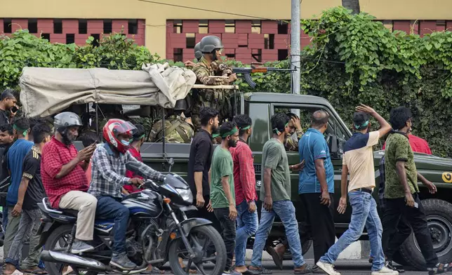 Military personnel stand guard on a street as members of Bangladesh Nationalist Party (BNP) walk to take part in a rally in front of the party's headquarters in Dhaka, Bangladesh, Wednesday, Aug. 7, 2024. (AP Photo/Rajib Dhar)