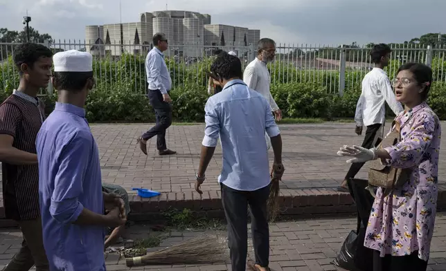 Students clean the area near the parliament building which was vandalised on Monday, in Dhaka, Bangladesh, Tuesday, Aug. 6, 2024. (AP Photo/Fatima Tuj Johora)