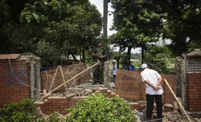 A man peeks inside the boundary wall of the vandalised house of Sheikh Hasina, who resigned as Prime Minister on Monday, in Dhaka, Bangladesh, Tuesday, Aug. 6, 2024. (AP Photo/Rajib Dhar)