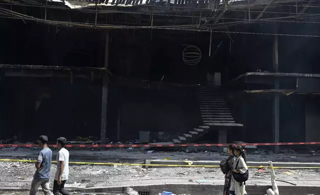 People walk past a vandalised shopping center in Dhaka, Bangladesh, Wednesday, Aug. 7, 2024. (AP Photo/Fatima Tuj Johora)