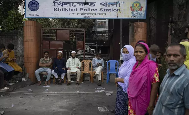 People keep guard in front of a police station which was vandalised on Monday, in Dhaka, Bangladesh, Tuesday, Aug. 6, 2024. (AP Photo/Fatima Tuj Johora)