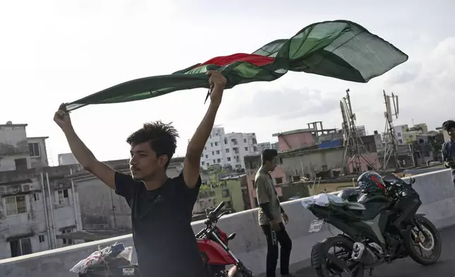 A boy celebrates with a national flag after the resignation of prime minister Sheikh Hasina in Dhaka, Bangladesh, Tuesday, Aug. 6, 2024. (AP Photo/Fatima Tuj Johora)