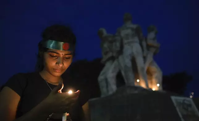 A girl participates in a candlelight vigil to pay tribute to victims of recent countrywide violence, in Dhaka, Bangladesh, Wednesday, Aug. 7, 2024. (AP Photo/Fatima Tuj Johora)