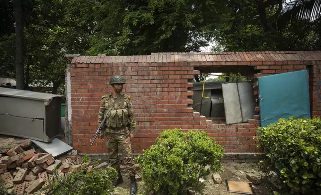 An army personnel stands guard in front of a vandalised boundary wall of Sheikh Hasina, who resigned as Prime Minister on Monday, in Dhaka, Bangladesh, Tuesday, Aug. 6, 2024. (AP Photo/Rajib Dhar)