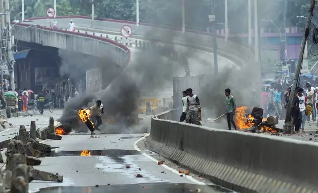 A protester throws a rubber tire on fire during a protest against Prime Minister Sheikh Hasina and her government, in Dhaka, Bangladesh, Monday, Aug. 5, 2024. (AP Photo/Rajib Dhar)