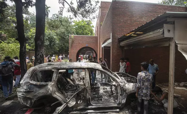 A burnt car stands in the vandalised house of Sheikh Hasina, who resigned as Prime Minister on Monday, in Dhaka, Bangladesh, Tuesday, Aug. 6, 2024. (AP Photo/Rajib Dhar)