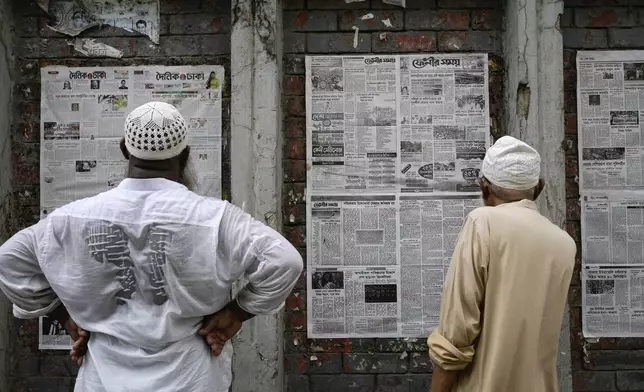 People read newspapers pasted on a wall in Dhaka, Bangladesh, Wednesday, Aug. 7, 2024. (AP Photo/Fatima Tuj Johora)