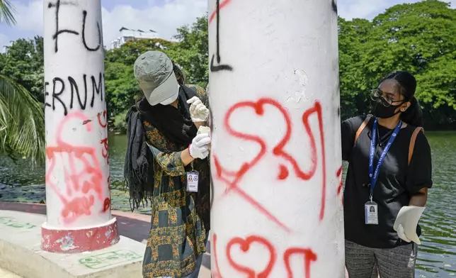 Students clean pillars that were vandalised with graffiti in Dhaka, Bangladesh, Wednesday, Aug. 7, 2024. (AP Photo/Fatima Tuj Johora)