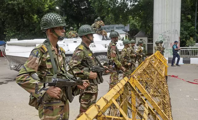 Army personnel stand guard behind a barrier during a curfew imposed following violence during protests against Prime Minister Sheikh Hasina and her government, in Dhaka, Bangladesh, Monday, Aug. 5, 2024. (AP Photo/Rajib Dhar)