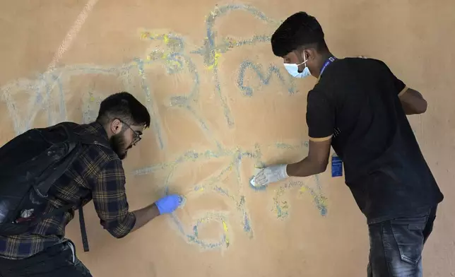 Students clean a wall that was vandalised with graffiti in Dhaka, Bangladesh, Wednesday, Aug. 7, 2024. (AP Photo/Fatima Tuj Johora)