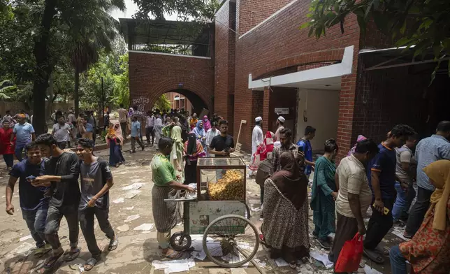 A man sells snacks as people visit the vandalised house of Sheikh Hasina, who resigned as Prime Minister on Monday, in Dhaka, Bangladesh, Tuesday, Aug. 6, 2024. (AP Photo/Rajib Dhar)