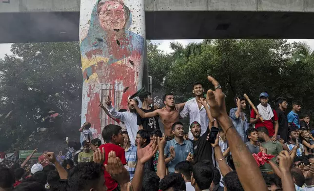 Protesters celebrate beside a defaced portrait of Prime Minister Sheikh Hasina after news of her resignation, in Dhaka, Bangladesh, Monday, Aug. 5, 2024. (AP Photo/Fatima Tuj Johora)