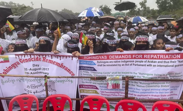 Rohingya refugees gather in the rain to demand safe return to Myanmar's Rakhine state as they mark the seventh anniversary of their mass exodus at their refugee camp at Kutupalong in Cox's Bazar district, Bangladesh, Sunday, Aug. 25, 2024. (AP Photo/ Shafiqur Rahman)