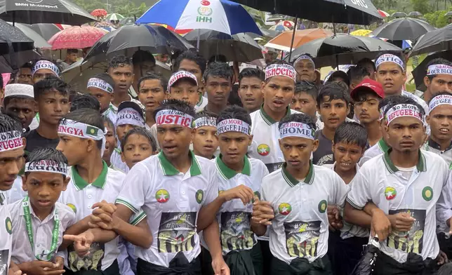 Rohingya refugees gather in the rain to demand safe return to Myanmar's Rakhine state as they mark the seventh anniversary of their mass exodus at their refugee camp at Kutupalong in Cox's Bazar district, Bangladesh, Sunday, Aug. 25, 2024. (AP Photo/ Shafiqur Rahman)