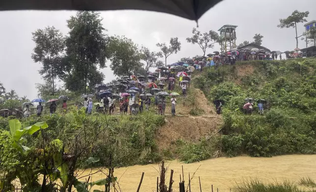 Rohingyas refugees gather in the rain to demand safe return to Myanmar's Rakhine state as they mark the seventh anniversary of their mass exodus from Myanmar at their refugee camp at Kutupalong in Cox's Bazar district, Bangladesh, Sunday, Aug. 25, 2024. (AP Photo/ Shafiqur Rahman)