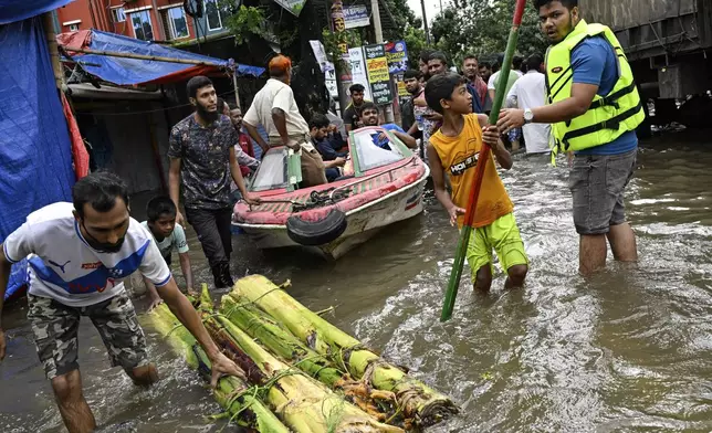 Volunteers use a boat to help rescue people on a flooded street following heavy rains in Mohipal, Feni, a coastal district in southeast Bangladesh, Friday, Aug. 23, 2024. (AP Photo/Fatima Tuj Johora)