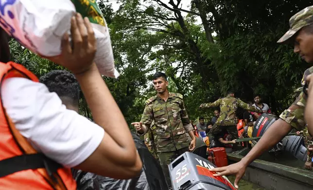 Bangladesh army personnel rescue people in a boat after heavy rains caused large areas to be flooded in Mohipal, Feni, a coastal district in southeast Bangladesh, Friday, Aug. 23, 2024. (AP Photo/Fatima Tuj Johora)