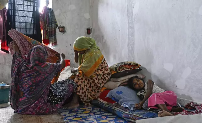 People displaced by floods rest at a relief shelter in Mohipal, Feni, a coastal district in southeast Bangladesh, Friday, Aug. 23, 2024. (AP Photo/Fatima Tuj Johora)