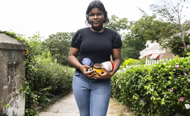 Mia Hall, 14, poses for a portrait in her neighborhood park while holding some skin care products she uses regularly on Thursday, Aug. 29, 2024, in the Bronx borough of New York. (AP Photo/Brittainy Newman)