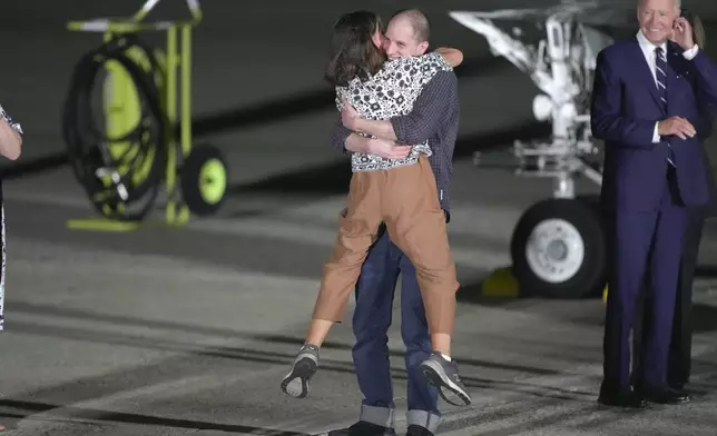 Reporter Evan Gershkovich hugs his mother, Ella Milman, as President Joe Biden, right, looks on at Andrews Air Force Base, Md., following their release as part of a 24-person prisoner swap between Russia and the United States, Thursday, Aug. 1, 2024. (AP Photo/Manuel Balce Ceneta)