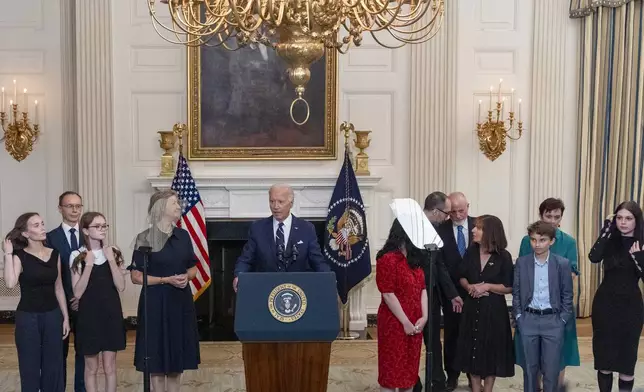 Bibi Butorin, Pavel Butorin, Miriam Butorin, Elizabeth Whelan, President Joe Biden, Danielle Gershkovich, Anthony Huczek, Mikhail Gershkovich, Ella Milman, Daniil Kara-Murza, Evgeniya Kara-Murz, and Ekaterina Kara-Murza, as Biden delivers remarks on a prisoner swap with Russia from the State Dining Room of the White House, Thursday, Aug. 1, 2024, in Washington. (AP Photo/Alex Brandon)