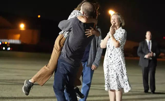 Reporter Evan Gershkovich hugs his mother Ella Milman, left, at Andrews Air Force Base, Md., following his release as part of a 24-person prisoner swap between Russia and the United States, Thursday, Aug. 1, 2024. Looking on at right is Elizabeth Whelan, sister of released prisoner Paul Whelan. (AP Photo/Alex Brandon)