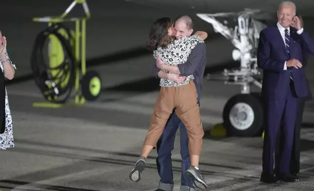 Reporter Evan Gershkovich hugs his mother, Ella Milman, as President Joe Biden, right, looks on at Andrews Air Force Base, Md., following their release as part of a 24-person prisoner swap between Russia and the United States, Thursday, Aug. 1, 2024. (AP Photo/Manuel Balce Ceneta)