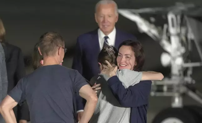 President Joe Biden looks on as Alsu Kurmasheva hugs a family member on the tarmac after arriving at Andrews Air Force Base, Md., following their release as part of a 24-person prisoner swap between Russia and the United States, Thursday, Aug. 1, 2024. (AP Photo/Manuel Balce Ceneta)