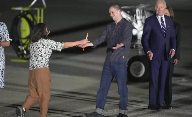 Reporter Evan Gershkovich, center, is greeted on the tarmac by his mother, Ella Milman, left, as President Joe Biden and Vice President Kamala Harris look on at Andrews Air Force Base, Md., following their release as part of a 24-person prisoner swap between Russia and the United States, Thursday, Aug. 1, 2024. (AP Photo/Manuel Balce Ceneta)