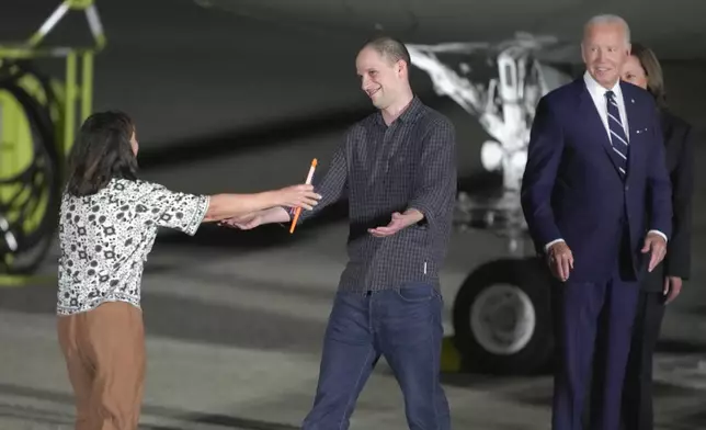 Reporter Evan Gershkovich, center, is greeted on the tarmac by his mother, Ella Milman, as President Joe Biden and Kamala Harris look on at Andrews Air Force Base, Md., following the release as part of a 24-person prisoner swap between Russia and the United States, Thursday, Aug. 1, 2024. (AP Photo/Manuel Balce Ceneta)