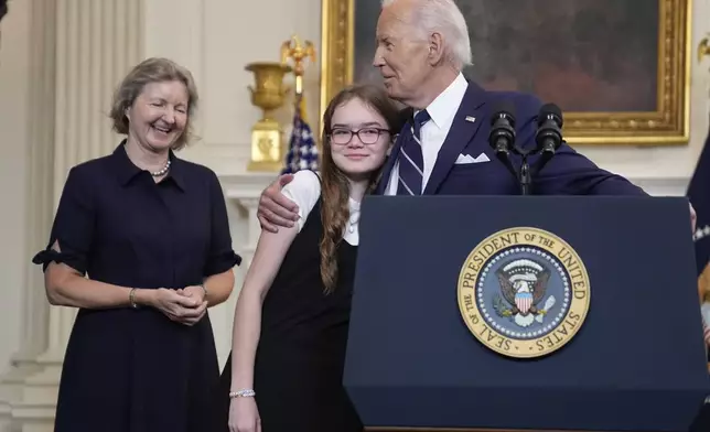 President Joe Biden, right, hugging Miriam Butorin, center, as Elizabeth Whelan, left, looks on after he delivered remarks on a prisoner swap with Russia from the State Dining Room of the White House, Thursday, Aug. 1, 2024, in Washington. (AP Photo/Evan Vucci)