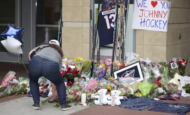 Kaitlin O'Hara of Columbus, places flowers at a memorial set up by fans for Blue Jackets hockey player Johnny Gaudreau in Columbus, Ohio, Aug. 30, 2024. Gaudreau, along with his brother Matthew, was fatally struck by a motorist while riding his bicycle on Thursday. (AP Photo/Joe Maiorana)