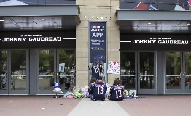 Shiloh Rivera, left, mourns with Hylas Stemen, center, and Amanda Rivera of Columbus at a memorial set up by fans for Blue Jackets hockey player Johnny Gaudreau in Columbus, Ohio, Aug. 30, 2024. Gaudreau, along with his brother Matthew, was fatally struck by a motorist while riding his bicycle on Thursday. (AP Photo/Joe Maiorana)