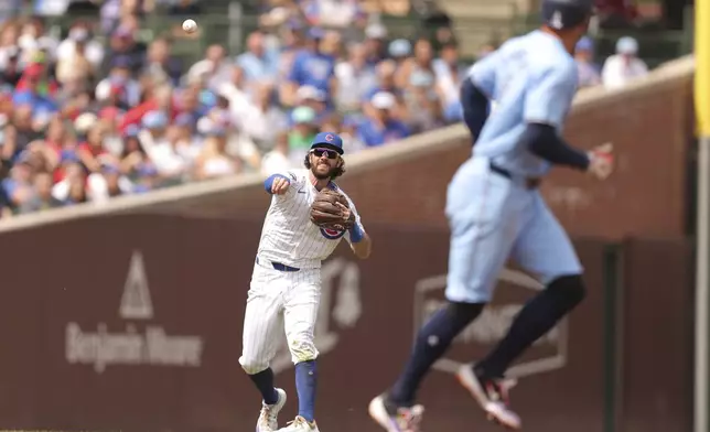 Chicago Cubs' Dansby Swanson, left, throws to first base for an out during the third inning of a baseball game against the Toronto Blue Jays, Sunday, Aug. 18, 2024, in Chicago. (AP Photo/Melissa Tamez)