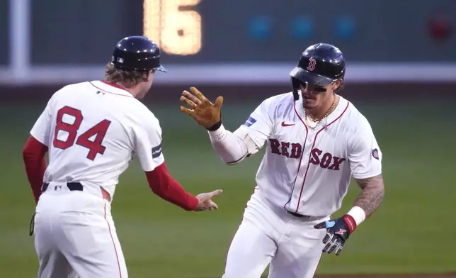 Boston Red Sox's Jarren Duran, right, is congratulated by third base coach Kyle Hudson while rounding the bases on his solo home run ball during the first inning of a baseball game against the Toronto Blue Jays at Fenway Park, Tuesday, Aug. 27, 2024, in Boston. (AP Photo/Charles Krupa)