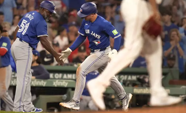 Toronto Blue Jays' Will Wagner is congratulated by third base coach Carlos Febles (51) after hitting a solo home run during the sixth inning of a baseball game against the Boston Red Sox at Fenway Park, Tuesday, Aug. 27, 2024, in Boston. (AP Photo/Charles Krupa)