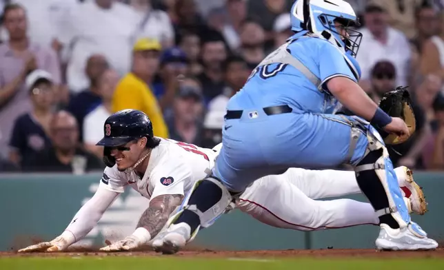 Boston Red Sox's Jarren Duran, left, beats the throw to Toronto Blue Jays catcher Alejandro Kirk to score on a single by Wilyer Abreu during the first inning of a baseball game at Fenway Park, Wednesday, Aug. 28, 2024, in Boston. (AP Photo/Charles Krupa)