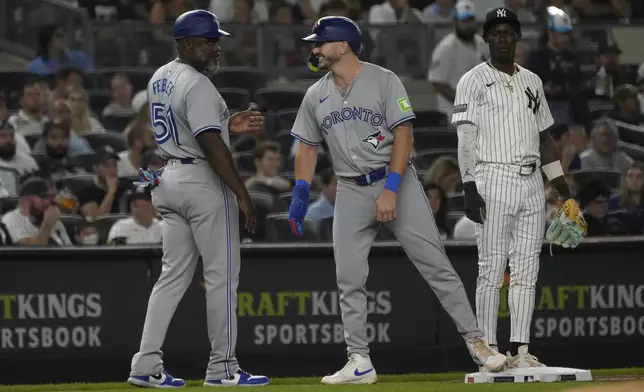 Toronto Blue Jays third base coach Carlos Febles, left, celebrates with Spencer Horwitz, center, after Horwitz ran to third on a single hit by Daulton Varsho during the first inning of a baseball game against the New York Yankees, Friday, Aug. 2, 2024, in New York. (AP Photo/Pamela Smith)