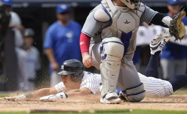 New York Yankees' Anthony Volpe, left, scores past Toronto Blue Jays catcher Alejandro Kirk, right, on a sacrifice fly hit by DJ LeMahieu during the sixth inning of a baseball game against the Toronto Blue Jays at Yankee Stadium, Sunday, Aug. 4, 2024, in New York. (AP Photo/Seth Wenig)