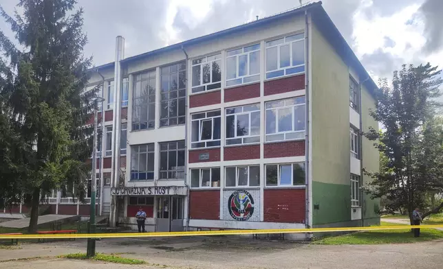 A police officer stands in front of a secondary school building in Sanski Most, northwest of Bosnia's capital, Sarajevo, Wednesday, Aug. 21, 2024, after a school employee shot and killed three people. (AP Photo/Edvin Zulic)