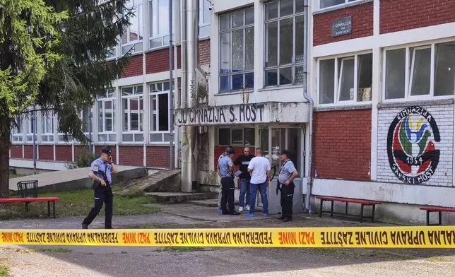 Police officers stand in front of a secondary school building in Sanski Most, northwest of Bosnia's capital, Sarajevo, Wednesday, Aug. 21, 2024, after a school employee shot and killed three people. (AP Photo/Edvin Zulic)