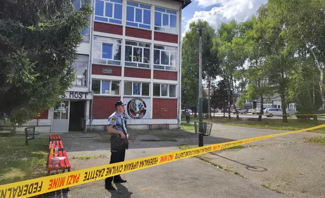 A police officer stands in front of a secondary school building in Sanski Most, northwest of Bosnia's capital, Sarajevo, Wednesday, Aug. 21, 2024, after a school employee shot and killed three people. (AP Photo/Edvin Zulic)